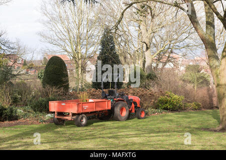 Kleiner orangener Traktor mit Anhänger, geparkt in einer Gartenanlage in Cusworth, Doncaster, South Yorkshire, England. Stockfoto
