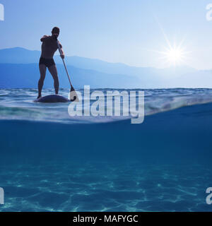 Stand up Paddle Boarding. Junger Mann, der auf einem SUP Board. Unterwasser Blick auf Meer, kopieren Platz für Text Stockfoto