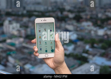 Bangkok, Thailand - 7 August 2016: Hand mit Apple iPhone 5 Handy die Pokemon Gehen, das am Bildschirm über das Bangkok Stadtbild phot Stockfoto