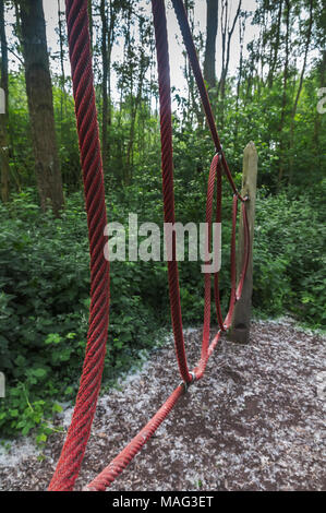 perspective of red rope suspended from a wooden pole placed in the forest Stockfoto