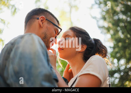 Schöne junge Paar küssen und umarmen in einem Sommer Park in der Nähe von Bäumen Stockfoto