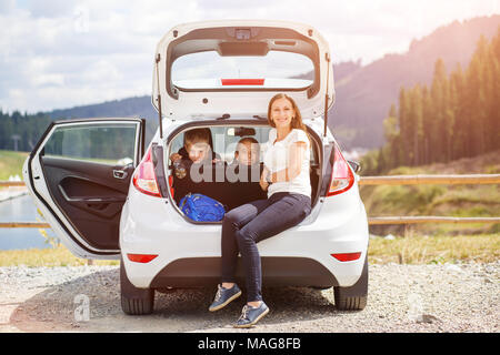 Familie Reisen mit dem Auto und in Ruhe in den geöffneten Kofferraum sitzen Stockfoto