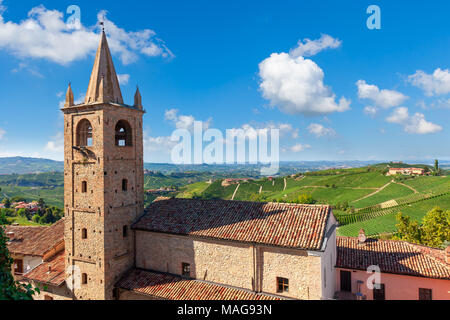 Alte Kirche Glockenturm und Hügel mit grünen Weinbergen auf Hintergrund unter blauem Himmel in Piemont, Norditalien. Stockfoto