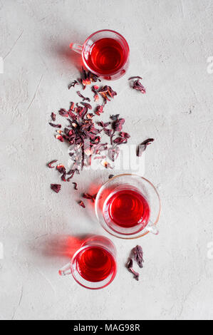 Baum Glas Tassen Hibiskus Tee auf die texturierte graue Tabelle, Ansicht von oben Stockfoto