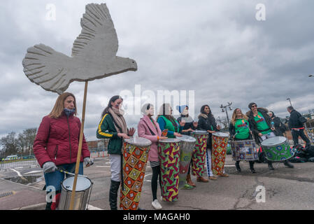 Aldermaston, UK. 1 Apr, 2018. Samba band TRibo spielt als CND der 60. Jahrestag der ersten Aldermaston März Tausende gegen die Bombe und geformte radikalen Protest für Generationen mobilisiert feiert. Ihr Protest außerhalb der Atomic Weapons Establishment ein Riese, iconic Symbol des Friedens, Reden, unter anderem durch einige von denen auf der ursprünglichen März enthalten, singen und trommeln und feierten den UN-Vertrag über das Verbot von Atomwaffen. Kampagne Atomwaffen abzuschaffen. Credit: Peter Marschall/Alamy leben Nachrichten Stockfoto