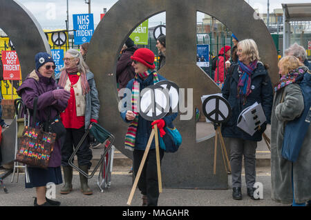 Aldermaston, UK. 1 Apr, 2018. CND errichtet seinen riesigen CND-Symbol Installation am Haupteingang der AWE Aldermaston der 60. Jahrestag der ersten Aldermaston März Tausende gegen die Bombe und geformte radikalen Protest für Generationen mobilisiert zu feiern. Ihr Protest außerhalb der Atomic Weapons Establishment ein Riese, iconic Symbol des Friedens, Reden, unter anderem durch einige von denen auf der ursprünglichen März enthalten, singen und trommeln und feierten den UN-Vertrag über das Verbot von Atomwaffen. Credit: Peter Marschall/Alamy leben Nachrichten Stockfoto