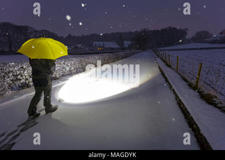 Flintshire, Wales, Vereinigtes Königreich 2. April 2018, UK Wetter: eine Auswaschung Ostern Feiertag endet mit einem Met Officer Wetter Warnung für Regen und Schnee für Feiertag Montag. Eine Person in Richtung der walkign Pantasaph Friary auf einem sehr verschneiten Morgen im Dorf von Pantasaph, Flintshire auf Ostern Feiertag Montag © DGDImages/Alamy leben Nachrichten Stockfoto