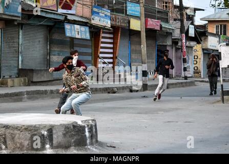 Srinagar, Indien. 2 Apr, 2018. Kaschmir Demonstranten werfen Steine gegen indische Polizisten (nicht dargestellt) bei Zusammenstößen in Srinagar, Indien verwalteten Kaschmir. Wie muslimische Mehrheit Bereiche von Kaschmir Montag beobachtete eine komplette Abschaltung der Tötung von 4 Zivilisten und 13 Rebellen in getrennten Begegnungen in Kaschmir zu protestieren. Behörden verhängten Ausgangssperre in mehreren Bereichen Straße Proteste zu stoppen. Der Aufruf für das Herunterfahren wurde von der separatistischen Gruppen gegeben. Mit Steinen bewerfen Vorfälle wurden von einigen Teilen der Kaschmir-tal berichtet. Inzwischen haben die Behörden auch ausgesetzt mobile Internet in Kas Stockfoto