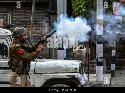 Srinagar, Indien. 2 Apr, 2018. Ein indischer Polizist feuert Tränengas Shell in Richtung Kaschmir Demonstranten bei einem Protest gegen die Tötungen in getrennten Begegnungen im Süden von Kaschmir. Mehrheit der muslimischen Gebiete von Kaschmir Montag beobachtete eine komplette Abschaltung der Tötung von 4 Zivilisten und 13 Rebellen in getrennten Begegnungen in Kaschmir zu protestieren. Credit: ZUMA Press, Inc./Alamy leben Nachrichten Stockfoto