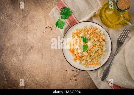 Bulgur Pilaw mit Huhn auf braunem Hintergrund Beton. Ansicht von oben, Platz für Text Stockfoto