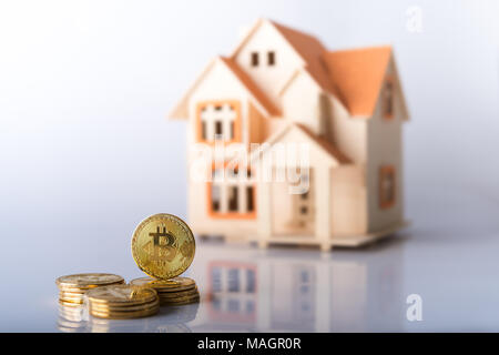 Konzept für den Kauf von Immobilien mit Bitcoins oder Vergleich der Preise der beiden Investitionen - Stapel der goldfarbenen Bitcoin Münzen scharf in Stockfoto