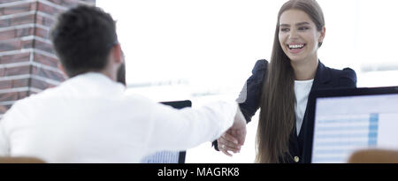 Handshake zwischen einem Client und einem Manager hinter einem Schreibtisch Stockfoto