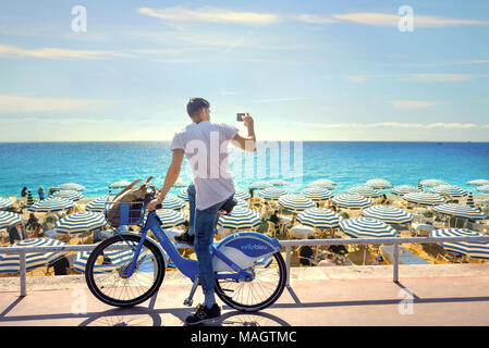 Street Scene mit Radfahrer und Sonnenschirme auf Luxus Strand. Nizza, Frankreich, Côte d'Azur Stockfoto
