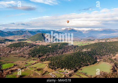 Heißluftballon fliegen mit croscat öffnen Vulkan und Bergen im Hintergrund, bewölkter Tag, Olot, Katalonien, Spanien Stockfoto