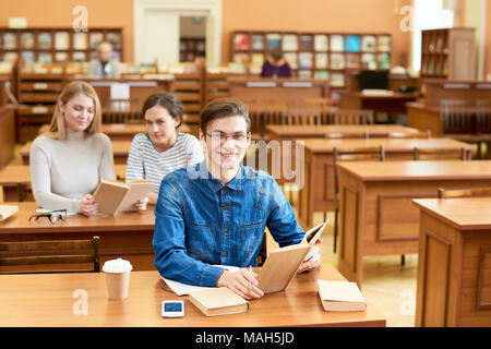 Aufgeregt fleissiger Student in Bibliothek Stockfoto