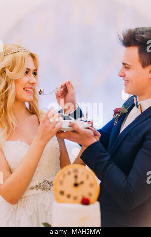 Hübscher Bräutigam seine schönen blonden Braut Fütterung mit Hochzeitstorte Stockfoto