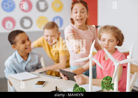 Fröhliches Mädchen zeigen auf Windenergieanlagen während der Gruppendiskussion Stockfoto