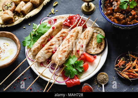 Chicken Kebab oder Shish Kebab mit gebratenem Gemüse und Sauce auf dunklem Hintergrund. Selektiver Fokus Stockfoto