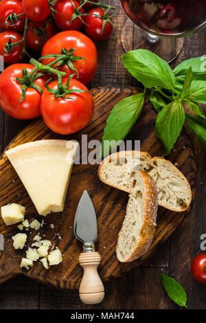 Parmesan, Ciabatta, Basilikum, frischen Tomaten und Glas Rotwein. Italienische Küche, italienische Küche. Ansicht von oben