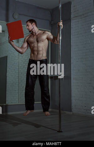 Männliche Acrobat levitates mit einem Buch, mit seiner Hand, das er auf die Stange hält. Stockfoto