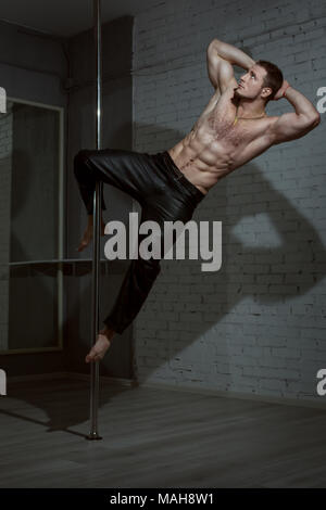 Mann, der an einer Stange tanzen zeigt Tricks. Stockfoto