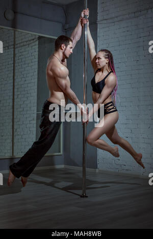 Paar an einer Stange tanzen zeigt sportliche Tricks. Stockfoto