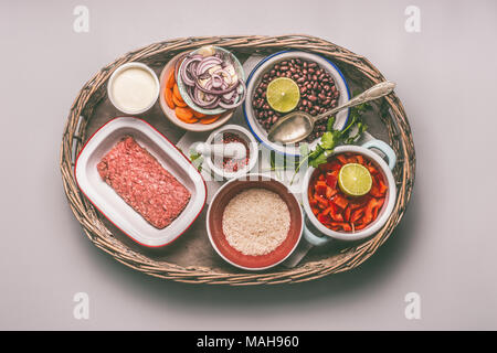 Schalen mit Zutaten für eine ausgewogene Mahlzeit eine Pfanne mit Bohnen, Hackfleisch, Reis und Gemüse in Fach auf grauem Hintergrund, Ansicht von oben Stockfoto