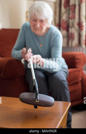 Ältere Frau mit Erreichen Arm Brillenetui zu Hause abholen Stockfoto