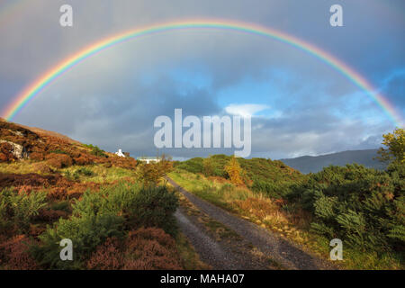 Regenbogen über North Strome, Lochcarron, Wester Ross in den schottischen Highlands, Schottland, Großbritannien, mit einem weit entfernten White Cottage eingebettet in den Hang ein. Stockfoto