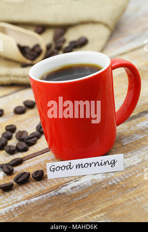 Guten Morgen Karte mit roten Becher Kaffee und verstreute Kaffeebohnen auf Holzmöbeln im Landhausstil Oberfläche Stockfoto