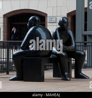 Zwei Männer auf einer Bank von Giles Penny (1962-) Giles Penny's Skulpturen menschlicher Figuren haben oft eine humorvolle Note in ihnen. Diese beiden Fellows sitzen in einem Stockfoto