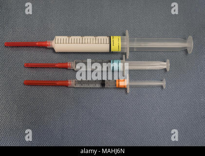 Spritzen mit der Anästhesie Agenten, Propofol, Fentanyl und Midazolam von oben fotografiert auf einem blauen Handtuch. Die Spritzen sind mit roten Sicherheit begrenzt Stockfoto