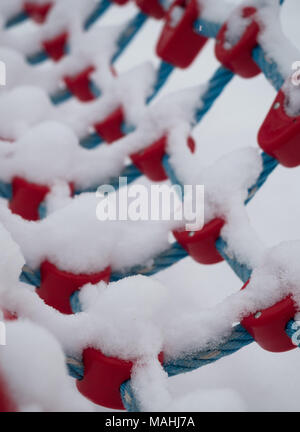 In der Nähe von Schnee bedeckt blau Seil und roten Stecker an Spielgeräten. Stockfoto