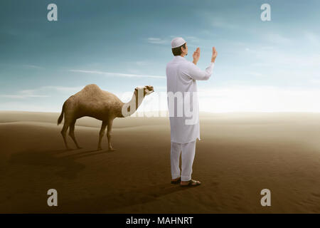 Seitenansicht des asiatischen muslimischen Mann mit Kamel auf den Dünen der Wüste Stockfoto