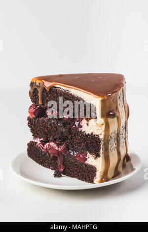 Nahaufnahme von Sweet cherry - Schokoladenkuchen mit Karamell auf Platte isoliert auf weißem Stockfoto