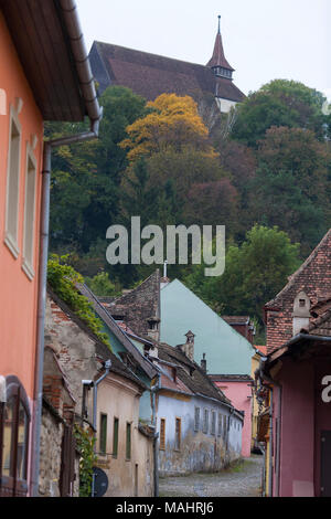 Gepflasterten Straßen führen vorbei an bunten alten Häusern zur Zitadelle in Sighisoara, Rumänien Stockfoto