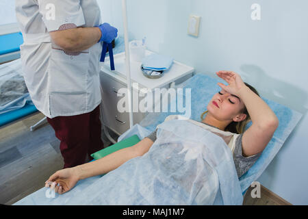 Krankenschwester macht eine Injektion mit einer Frau am OP-Tisch am Klinikum Vorbereitung Narkose medizinische Arztpraxis Konzept liegen. Stockfoto