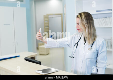 Lächelnd Krankenschwester selfies nehmen mit Ihrem Handy hinter der Rezeption Stockfoto