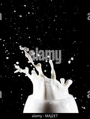 Milch/weiße Flüssigkeit splash aus Glas auf schwarzem Hintergrund Stockfoto