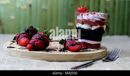 Dessert trifle mit Heidelbeere Sahne und Erdbeeren auf einem grünen Holz- Hintergrund Stockfoto