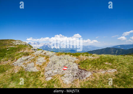 Wandern mark Zeichen rot weiss rot auf Rock am Berg Reiteralm mit Fernsicht auf die Berge Dachstein in Österreich lackiert Stockfoto