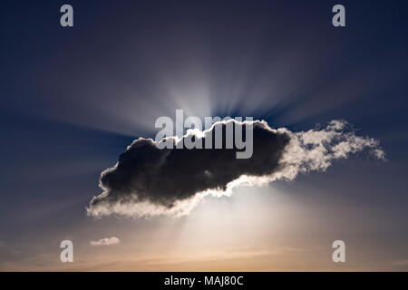 Sonnenstrahlen platzen hinter einer dunklen Cumulus cloud Stockfoto