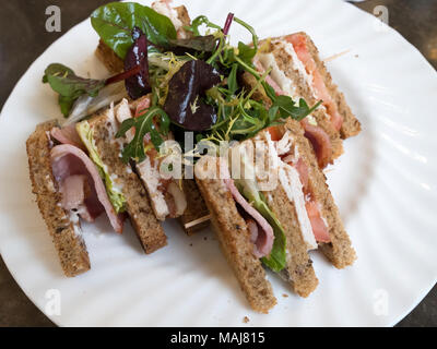 Café Mittagessen eine 2-layer Club Sandwich in braun Brot mit Speck Salat Tomate Huhn und Mayo mit Salat Stockfoto