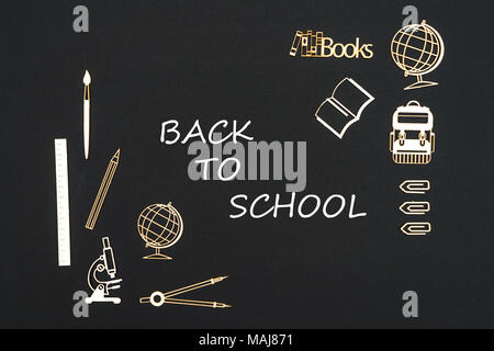 Schulbedarf auf schwarzem Hintergrund mit Text Zurück zur Schule Stockfoto