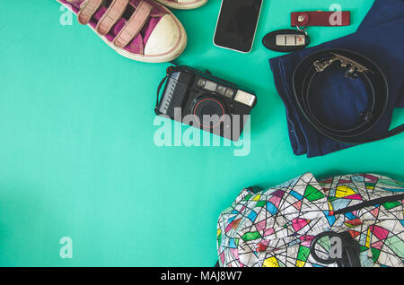 Traveler Zubehör. Schuhe, Taschen und Telefon auf dem grünen Hintergrund. Stockfoto