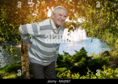 Alten Menschen mit Rückenschmerzen outdoor. Senior Großvater leiden unter Rückenschmerzen in den Park. Stockfoto