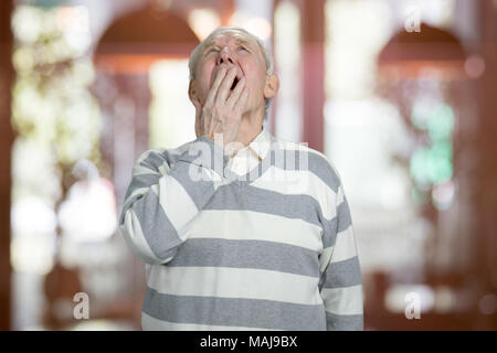 Portrait von gähnen Senior. Kaukasische alte Mann ist Gähnen, abstrakte verschwommenen Hintergrund. Stockfoto