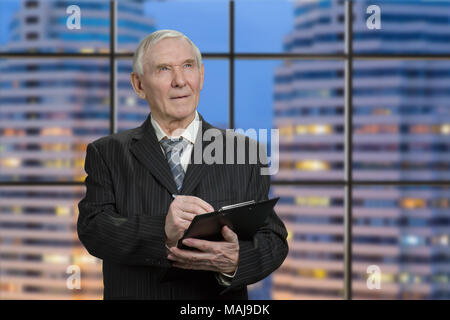 Älterer Mann im schwarzen Anzug schreiben auf Zwischenablage Papier. Suchen und aufschreiben. In skyscrapper in der Nacht. Stockfoto