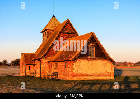 England, Kent, Fairfield. Der hl. Thomas Becket Kirche auf Romney Marsh beleuchtet Golden orange Licht, das von dem (unsichtbaren) sunrise. Stockfoto