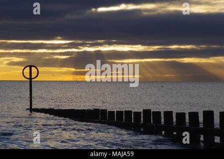 Firery Sonnenaufgang über der Nordsee in einer ruhigen Morgen, Strand Groyne im Vordergrund. Strand von Aberdeen, Schottland, Großbritannien. März 2018. Stockfoto